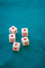 Dice for playing poker, with four figures of the ace and one of the tey, on a green mat.