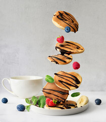 Flying pancakes and berries topped with chocolate syrup,