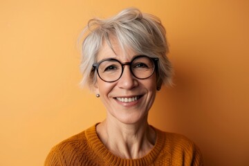 Portrait of smiling senior woman in eyeglasses on orange background