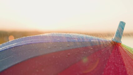 Colorful parasol under spring rainfall. Multicolored umbrella spins gracefully offering splash of colors against backdrop of dreary weather