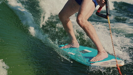 Wakesurfing. A man who is a beginner wakesurfer glides through the water behind a boat. Close-up of...