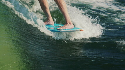 Wakesurfing. A man who is a beginner wakesurfer glides through the water behind a boat. Close-up of...