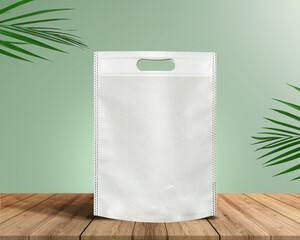 White Color Eco Friendly Tote Bag With Loop Strap. Non Woven Fabric Bag isolated on wood table with plants green background With copyspace for text