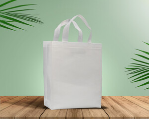 White Color Eco Friendly Tote Bag With Loop Strap. Non Woven Fabric Bag isolated on wood table with plants green background With copyspace for text