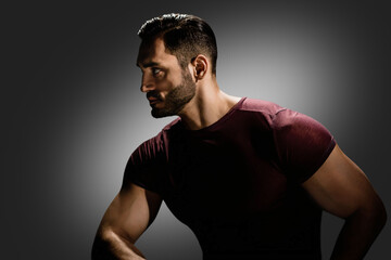 Studio portrait of young muscular bearded man looking to the side, Intensity captured: Dark and...