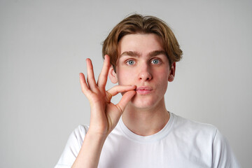 Young Man Performing Hand Gesture Near Face Against Plain Background - Powered by Adobe