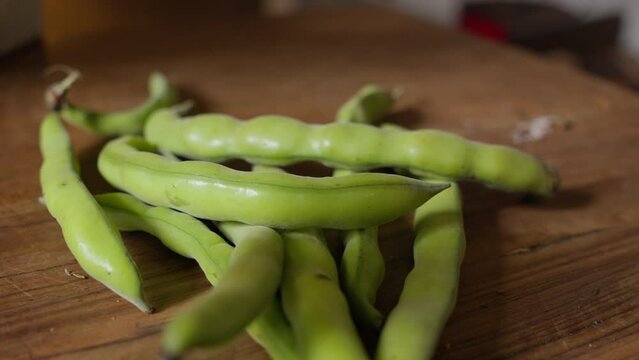 Fresh green broad beans on wooden surface.