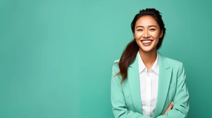 A successful East Asian businesswoman in her late 20s, against a gentle mint green background, flashing a radiant smile © Hanna Haradzetska