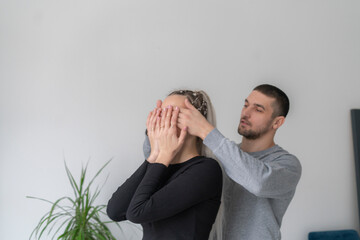 man and woman covering eyes from behind and making a surprise