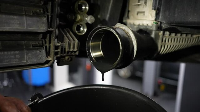 dirty diesel engine oil dropping from intercooler pipe during maintenance in repair shop. Slow motion
