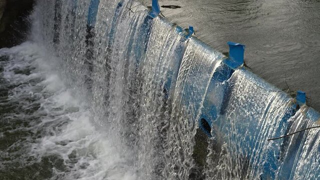 Clean sustainable river energy hydro electric dam with reservoir waterfalls creating hydropower renewable energy. Above view in slow motion