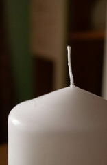 Close-up view of an unlit white candle's wick, poised and untouched, against a soft-focus...