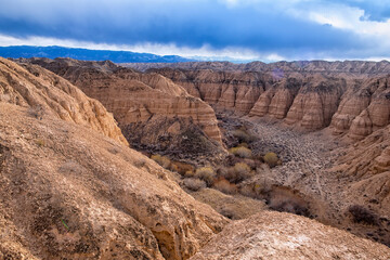 Sandy relief canyons carved by water and wind, reminiscent of a lunar and Martian landscape against...