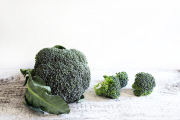 Broccoli freschi sulla tavola di legno, fondo bianco. Cibo sano e vegetariano. Copia spazio.