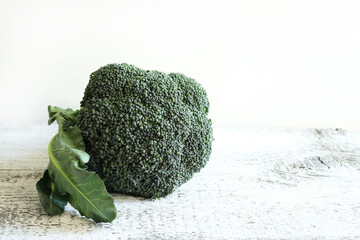 Broccoli freschi sulla tavola di legno, fondo bianco. Cibo sano e vegetariano. Copia spazio.
