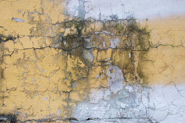 Surface of an old wall with yellow plaster with cracks and paint stains