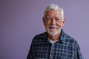 Portrait of a happy senior man smiling at the camera while standing against purple background