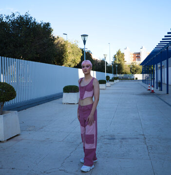 Young gay guy with pink hair and makeup walks down the street and poses for the photo. The boy is dressed in pink with modern clothes. Concept of equality and LGBTQ rights.