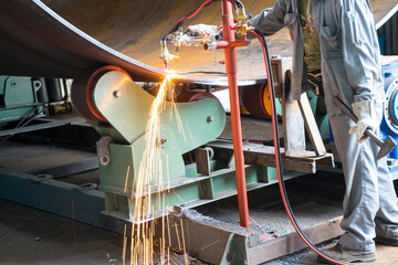 Welding machine with sparks and flashes. Worker and welder welding pipe metal at system assembled in gas and oil refinery plant workshop at the industry.