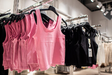 T-shirts, tops in pink and black colors on a hanger in a store
Women's clothing on hangers in a...