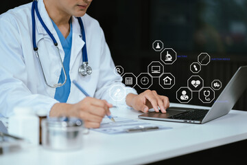 Doctor working on laptop computer and tablet and medical stethoscope on clipboard on desk, electronics medical record system EMRs concept.