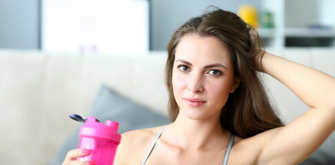 Beautiful girl holds sports water bottle, training. Home fitness is key element in weight loss program. Close-up girl drinks water for physical activity and stamina during training.