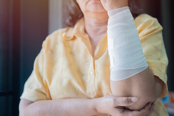 Shot of older Asian woman with gauze bandage wrapped around her arm.