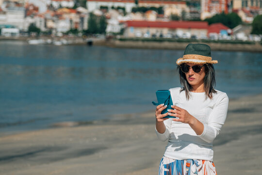 young woman using mobile phone on the beach