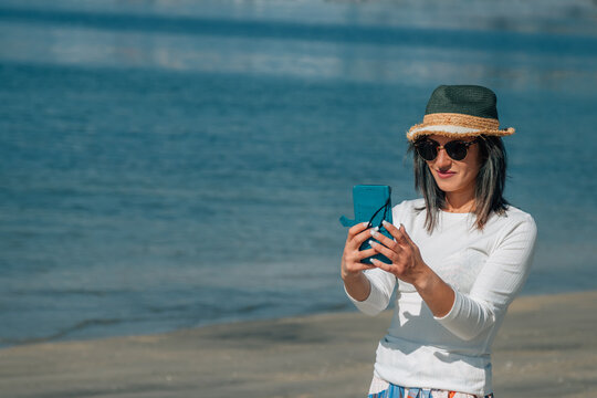 young woman using mobile phone on the beach