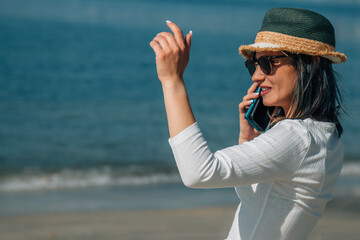 young woman with mobile phone on the beach and say hello