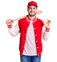 Young handsome man holding baseball bat and ball looking positive and happy standing and smiling with a confident smile showing teeth