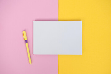 Clipboard with a white sheet and a pen on a colored background. View from above. place for text