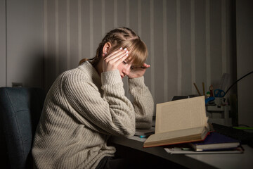 Fototapeta premium An overworked student falls asleep reading a book in the dark. Overtime processing. Study after work