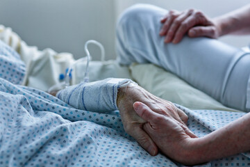 Close-up of senior woman holding hand of her caregiver in hospital