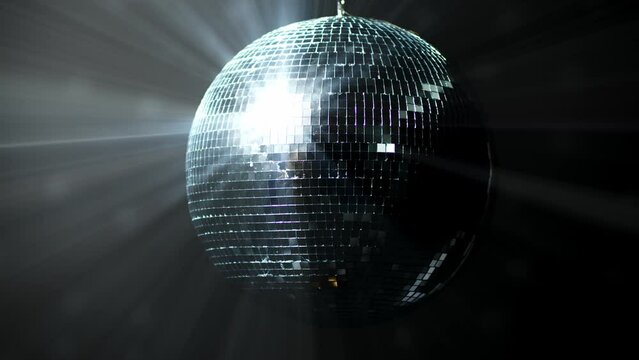 Disco ball with rotating reflected moving rays. Isolated disco ball on black background. Close-up. Mirror ball indoors.