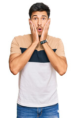 Young handsome man wearing casual clothes afraid and shocked, surprise and amazed expression with hands on face