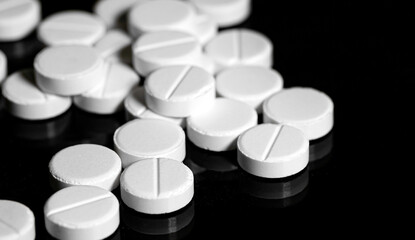 Obraz na płótnie Canvas Close up of white painkiller tablet on a reflective black backgr