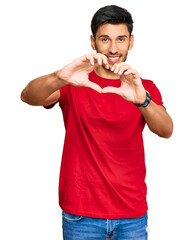 Young handsome man wearing casual red tshirt smiling in love doing heart symbol shape with hands. romantic concept.