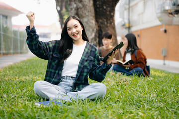 Asian Students are studying the campus park. Young people are spending time together. Reading book, working with laptop and tablet