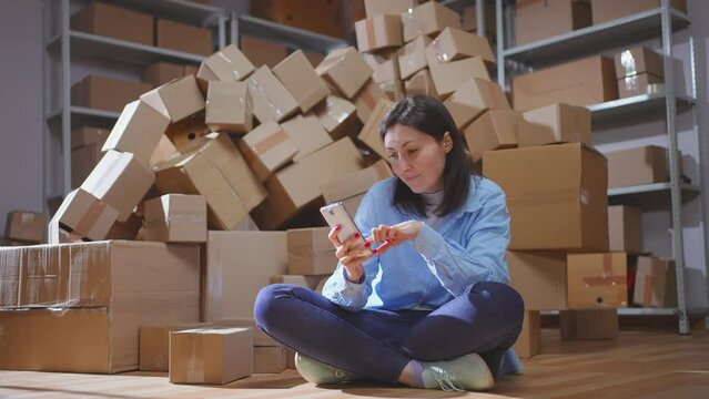 a piles of cardboard boxes female scans the QR code with the phone