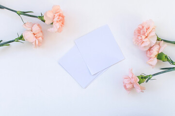 White sheets for notes lie near pink carnation flowers