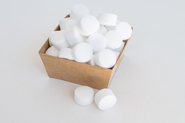 White tablets of pressed salt for the dishwasher close-up. Place for text