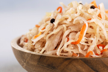 Sauerkraut with carrots and pepper in wooden bowl.