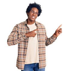 Handsome african american man with afro hair wearing casual clothes and glasses smiling and looking...
