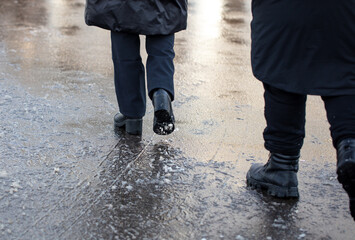 A man and a woman are walking through a puddle on a cold winter day