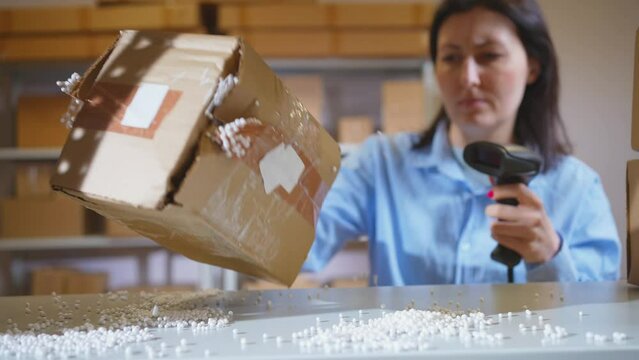 a damaged parcel,a broken female box is checked by a warehouse worker with a barcode scanner