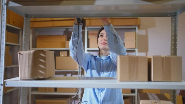 a female warehouse worker or an online store manager at work, arranging parcel boxes