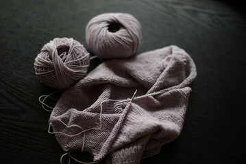 knitting project in pale purple color, seen on a black background
