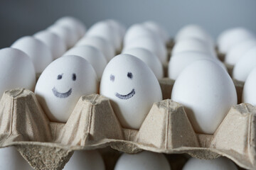 Eggs with smiley faces in carton box, closeup