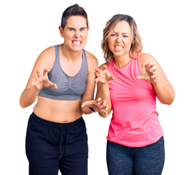 Couple of women wearing sportswear smiling funny doing claw gesture as cat, aggressive and sexy expression